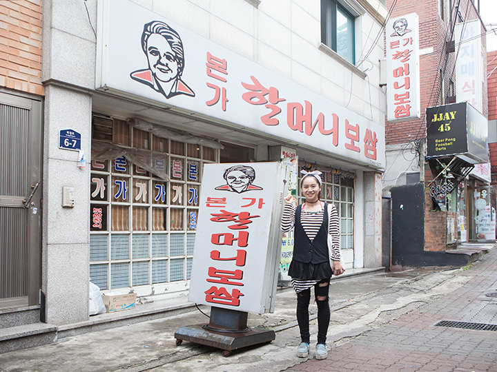 おばあさんの絵がどーんと描かれた看板の前でパチリ