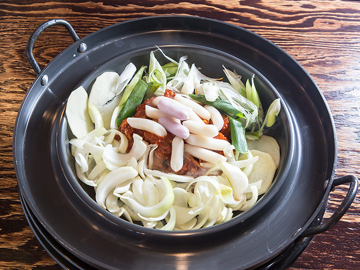 鉄板の上で鶏肉やキャベツなどの野菜を炒めます