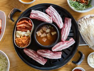 キムチと豆もやしのナムルを鉄板の上に乗せ、ゆっくりと温めます。鉄板が熱くなったら、豚肉を乗せます。