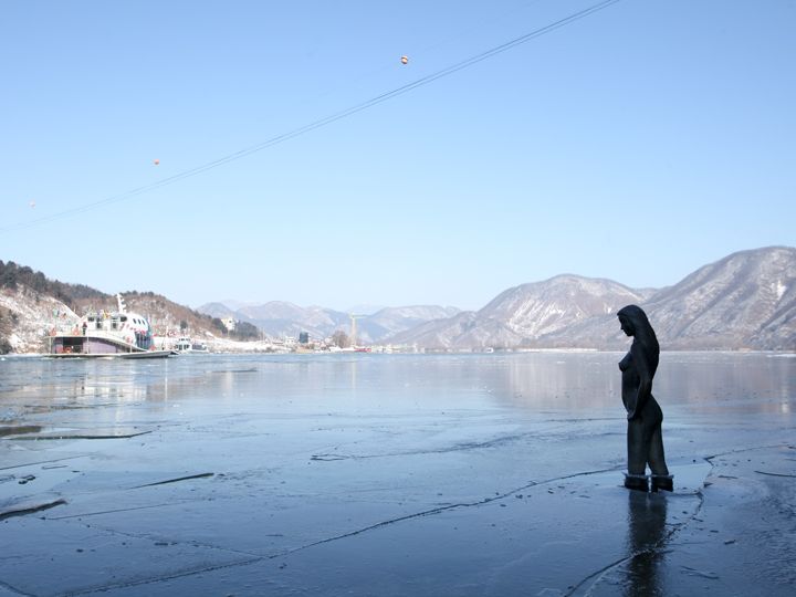 湖の前に佇む少女像