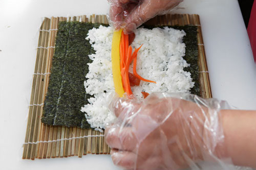 4.たくわん、炒めたニンジン、ほうれん草の和え物、ごぼうの煮付け、玉子焼き、ハムを順に入れていきます。