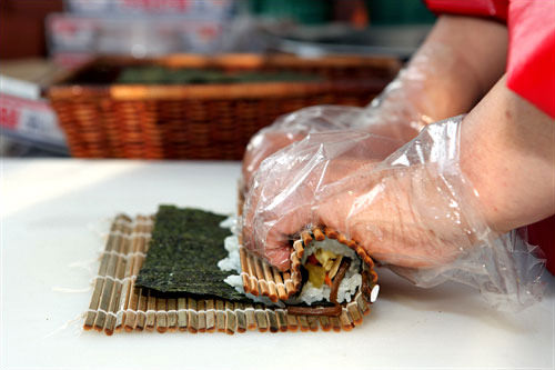 5.具があふれ出ないように巻きすでギュッと押しながら巻きます。