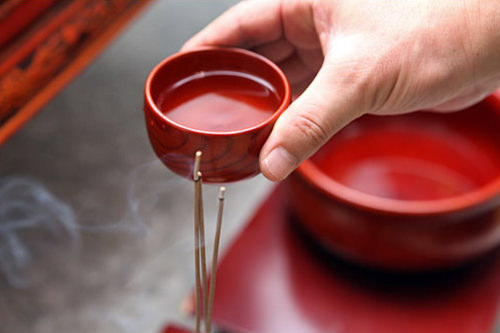 祭主が線香の上で酒の入った杯を回す