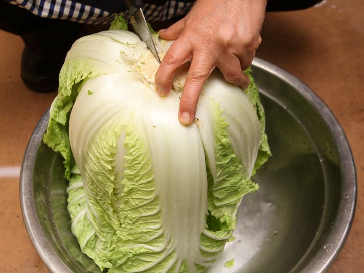 1.中央まで切り込みを入れ、手で裂くようにして2等分する。葉先まで包丁を入れないのは、先端の葉がバラバラになるのを防ぐため。