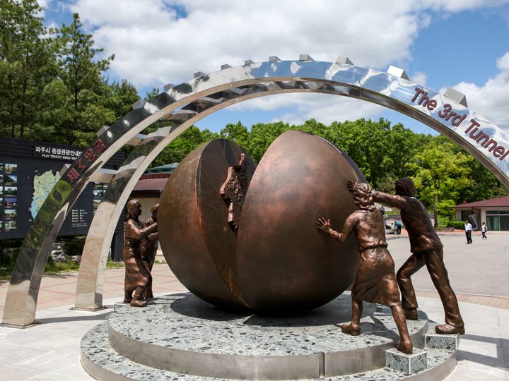 韓国と北朝鮮がそれぞれ描かれた半球をひとつにしようと南北の人々が両側から押している像